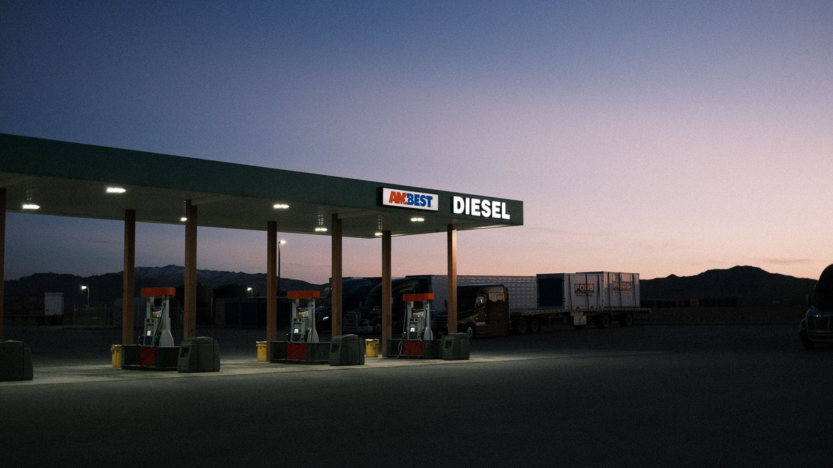 Truck stop diesel canopy at dusk with trailers parked behind, illustrating the linehaul vs all-in rate fuel surcharge math for 2026
